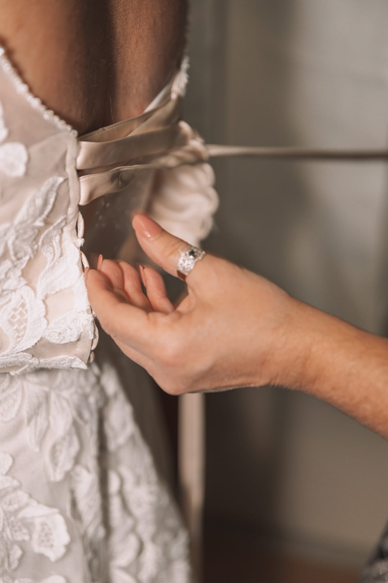 Getting ready: lacing the back of a lace wedding gown