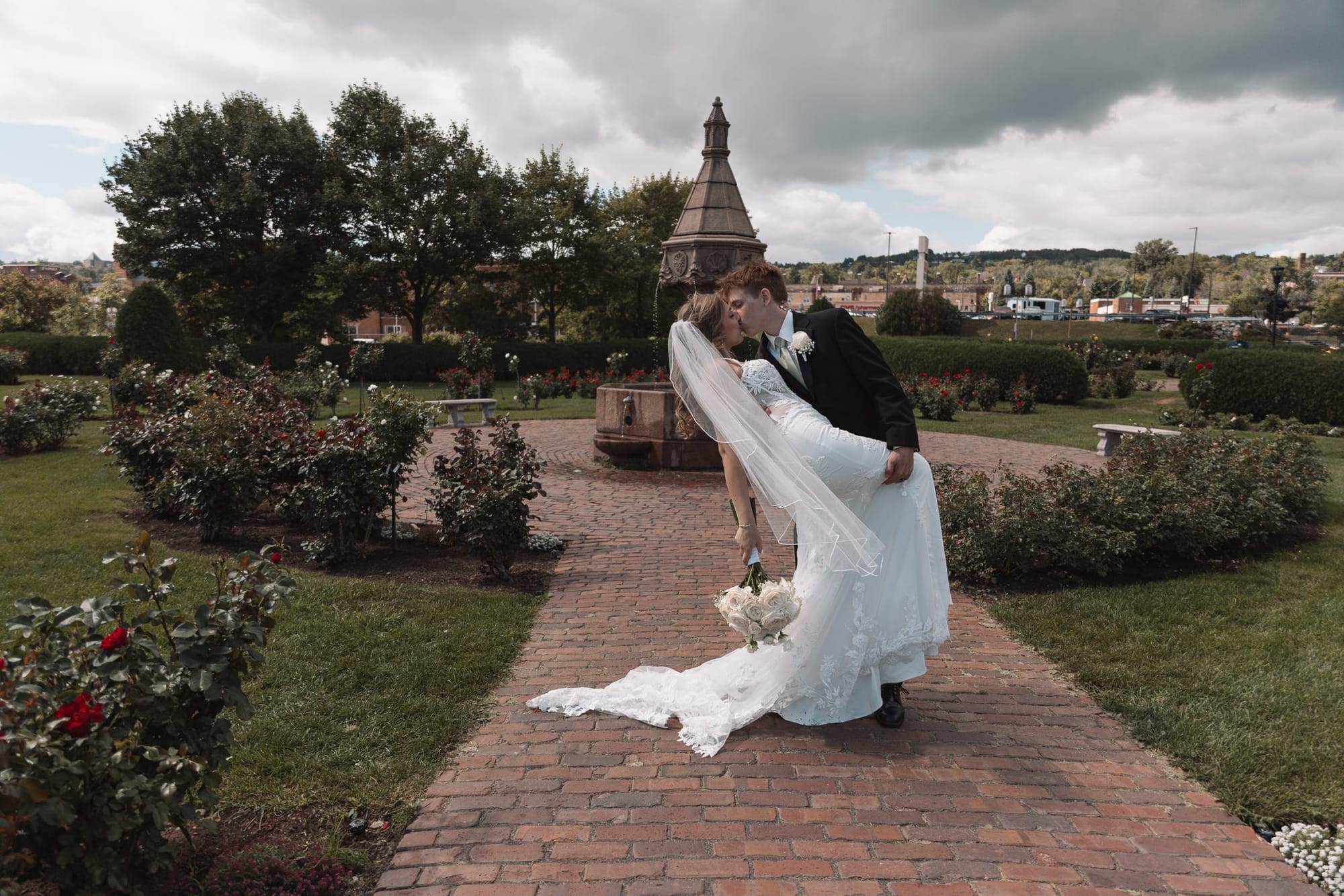 Bride and groom sharing a dip kiss in a rose garden