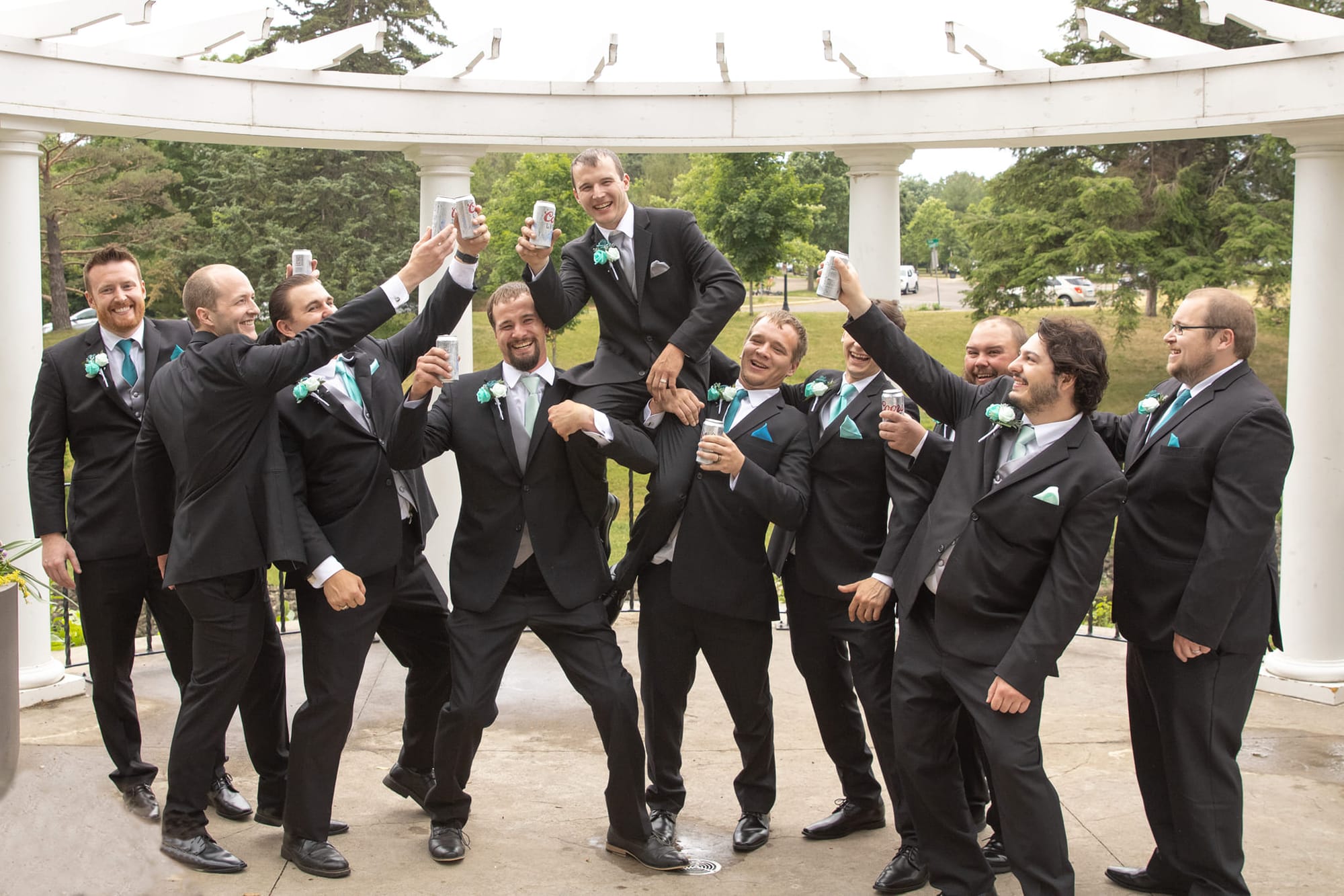 Groomsmen raising a toast under a garden pavilion