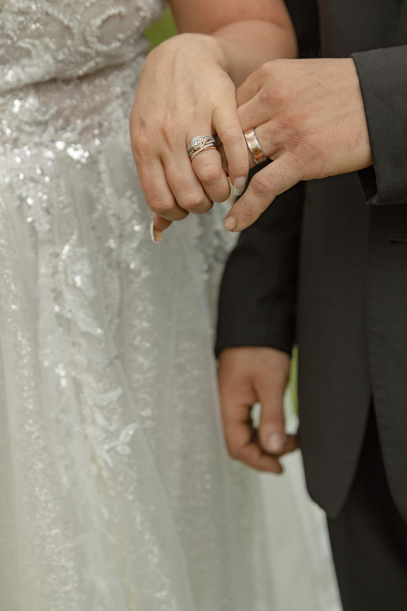 Close-up of the couple's hands and wedding rings against the gown