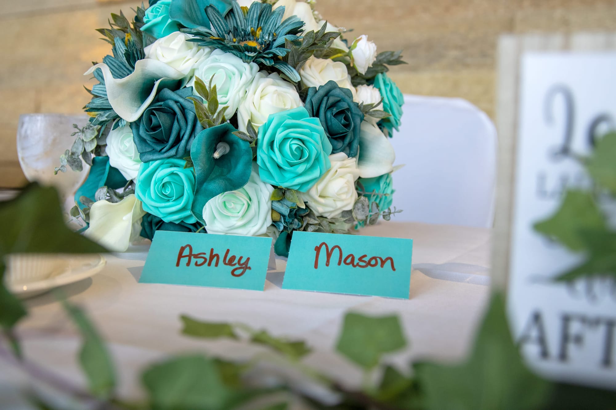 Teal and ivory bridal bouquet beside reception place cards